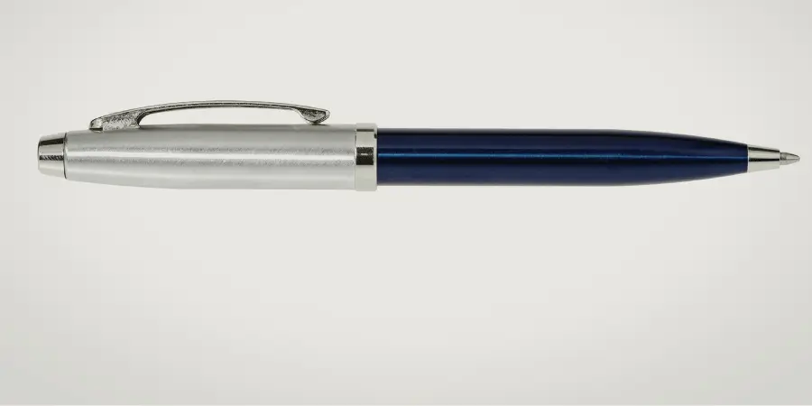 Blue and silver ballpoint pen placed horizontally on plain background, a common writing tool close to 6 inches for size reference