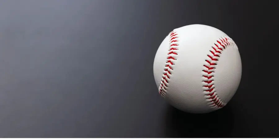 Single baseball on dark surface showing standard size, a familiar sports object helpful for estimating dimensions close to inches