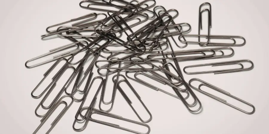 Pile of metal paper clips scattered randomly, small office items that can be aligned to estimate length measurements visually
