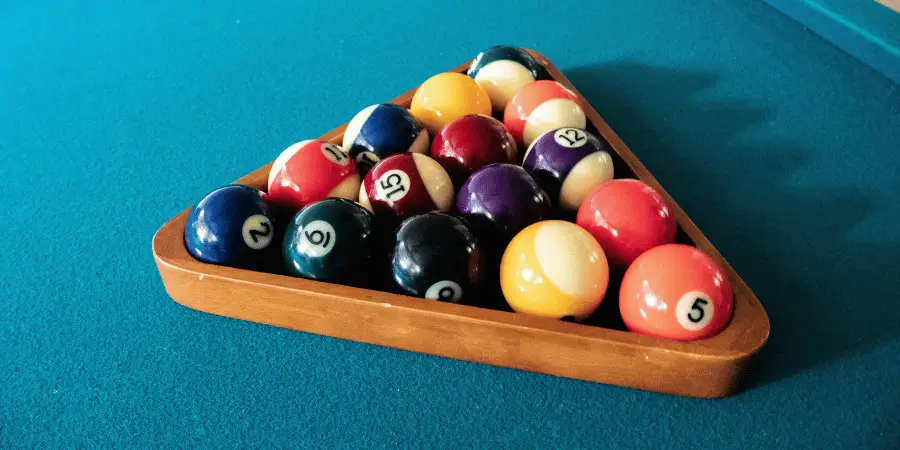 Triangle rack filled with colorful billiard balls on pool table, game setup with sharp detail and lighting