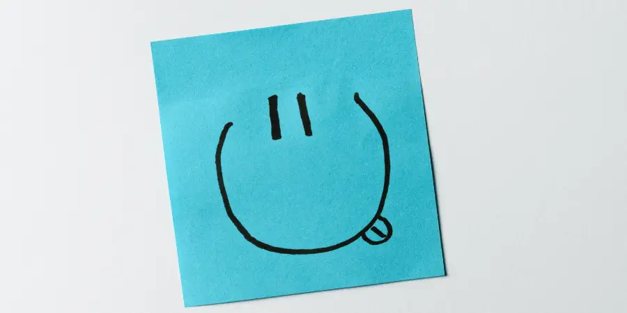 Blue sticky note with simple drawn face, small square paper around 3 inches wide useful for estimating combined 6 inch length