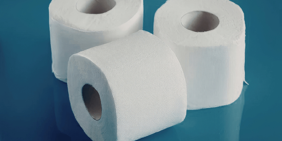 Three white toilet paper rolls arranged together on a smooth blue background surface