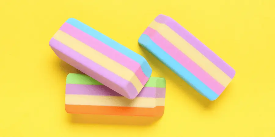 Three striped pastel erasers placed on a bright yellow background, soft texture and colorful stationery concept