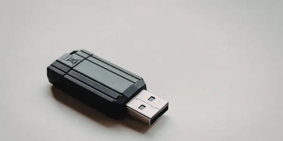 Black USB flash drive placed on a neutral surface, compact storage device close-up with minimal background