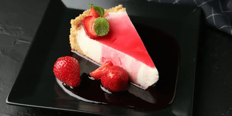 Strawberry cheesecake slice served on black dessert plate showing standard dessert plate size