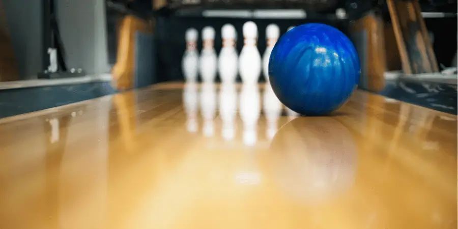 Bowling lane with bowling ball and pins representing half of a standard bowling pin length