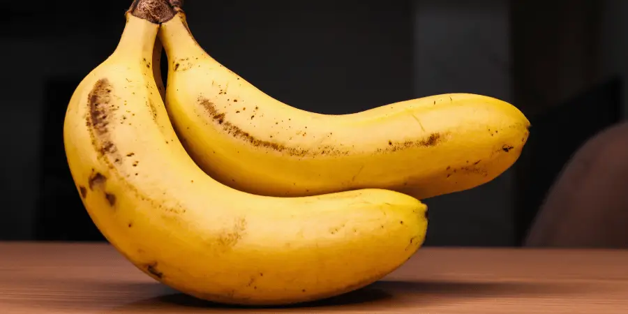Medium sized ripe bananas displayed on wooden table as natural things that are 7 inches long